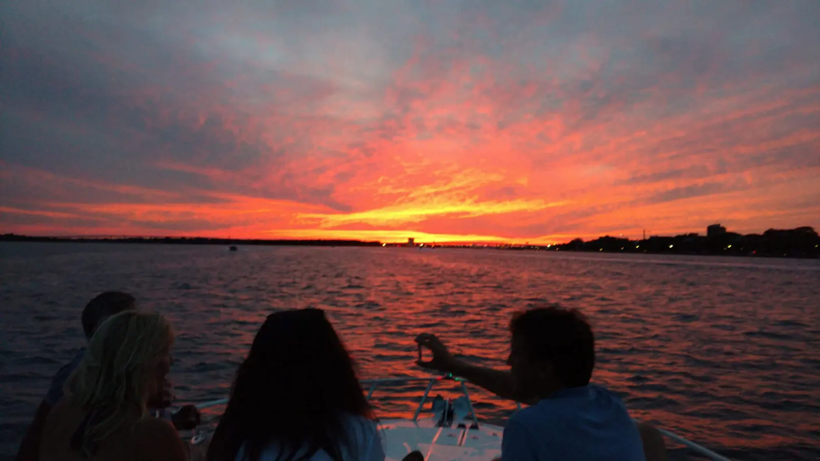 Guests watching the sunset from the back of a charter boat on Charleston harbor