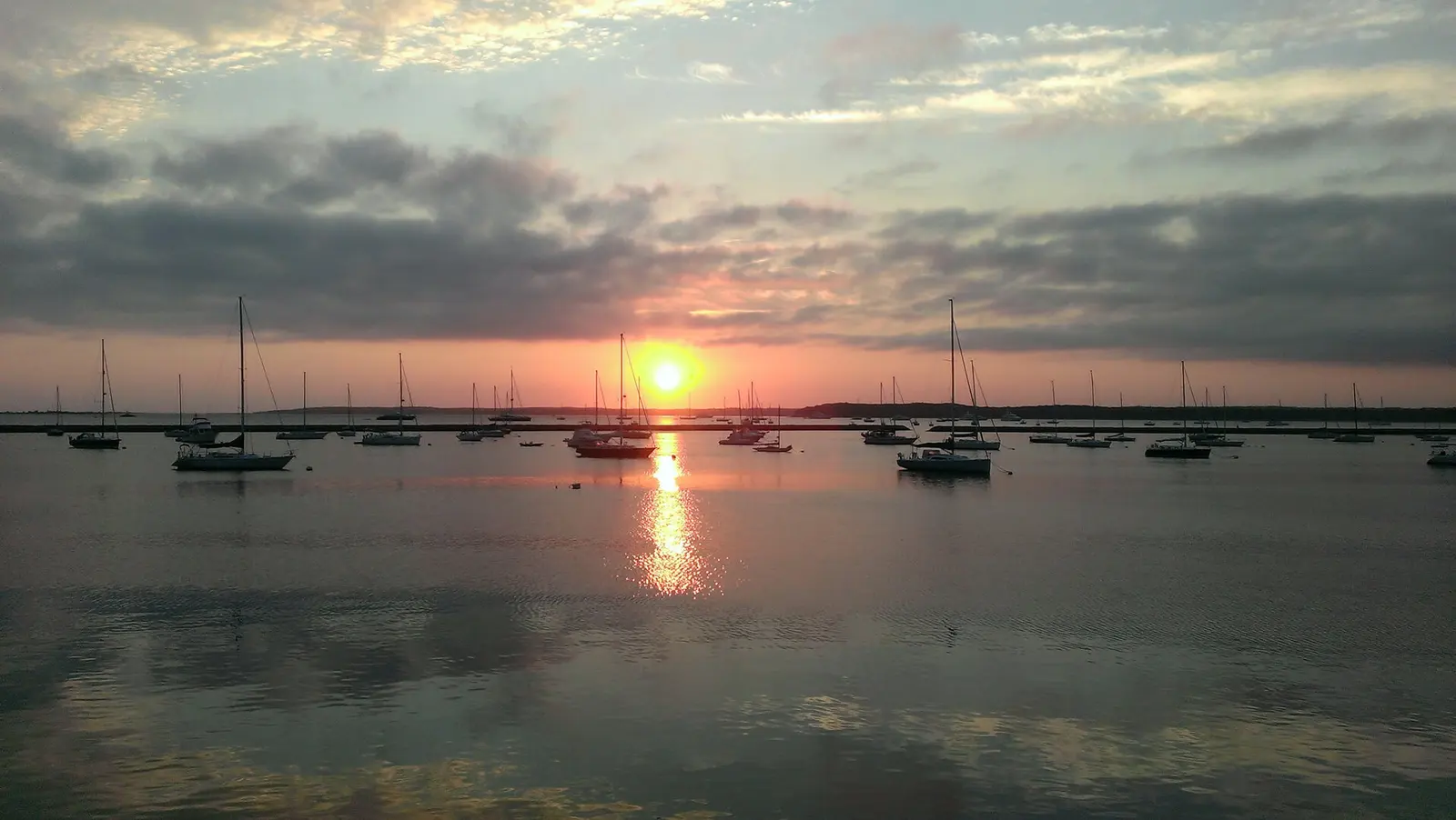 Sailboats anchored in Charleston harbor at sunset