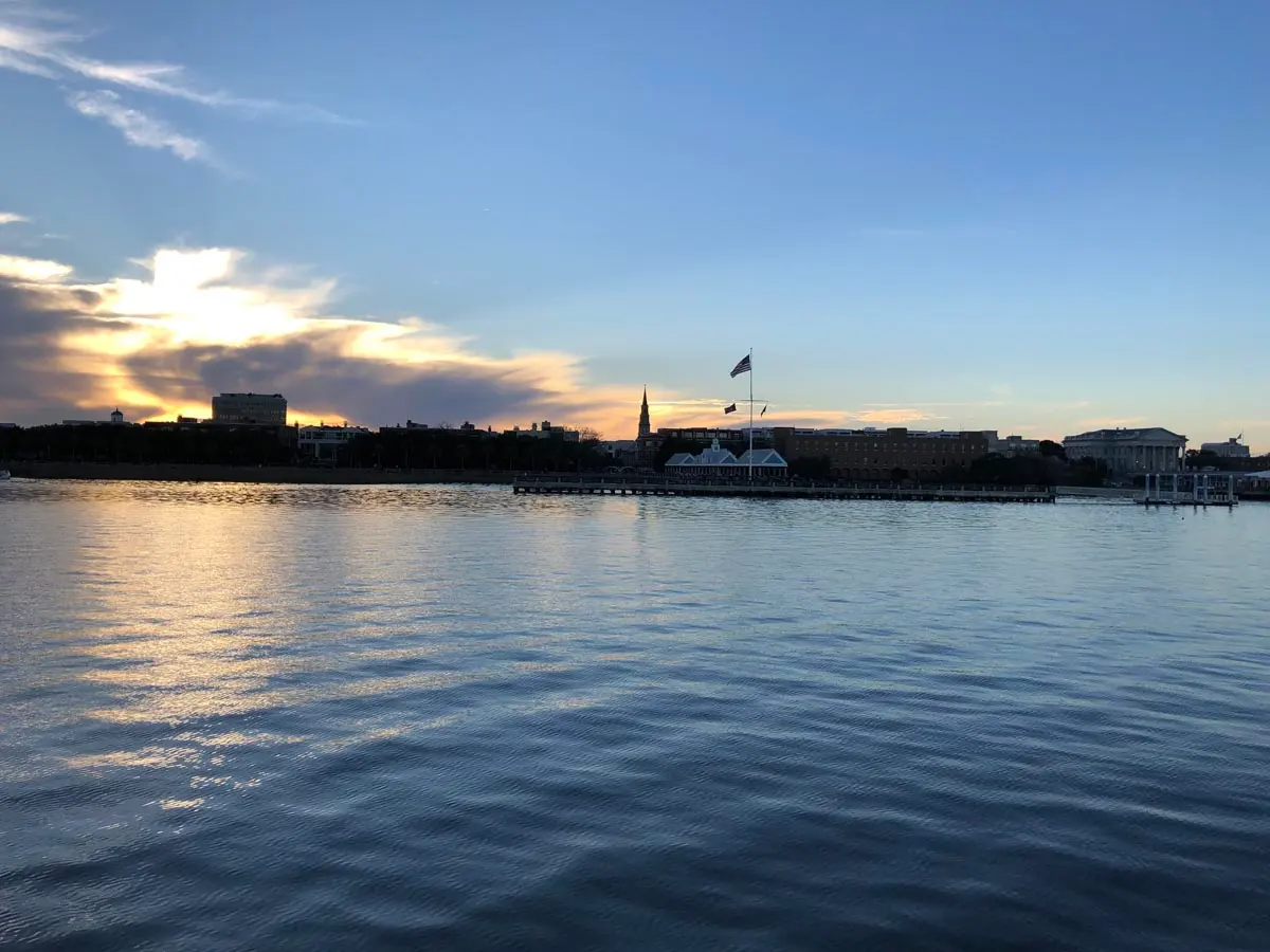 Fort Sumter and the Charleston harbor skyline at dusk with the American flag flying